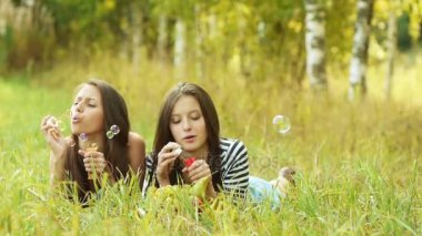 İki güzel genç kadın yeşil çim üzerinde yalan ve sabun köpüğü açıldığı.