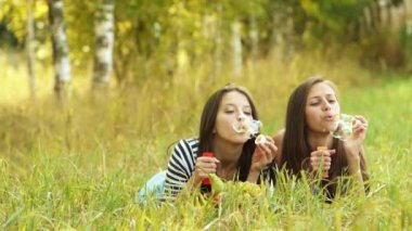 İki güzel genç kadın yeşil çim üzerinde yalan ve sabun köpüğü açıldığı.