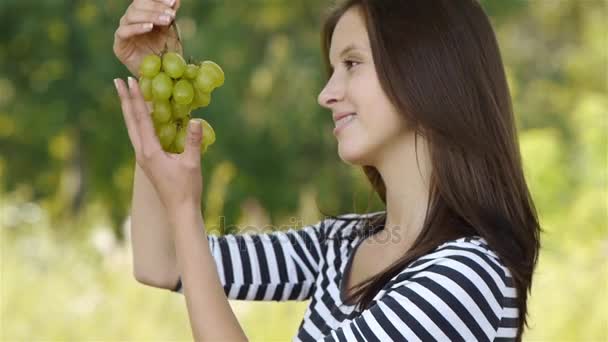 Приваблива красива жінка підняла голову, тримаючи грона винограду над відкритим ротом — стокове відео