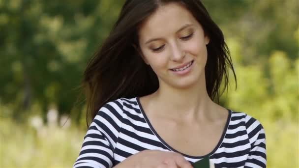 Güzel genç gülümseyen kadın karşı yeşil yaz Park kitap okuma. — Stok video