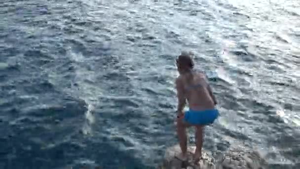 Lilla vackra flicka hoppa från sten till havet på Adriatiska kusten i Kroatien. — Stockvideo