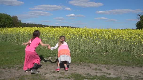 Movimento lento: Duas belas irmãzinhas alegremente pulando no parque da cidade de verão contra o pôr do sol de fundo . — Vídeo de Stock