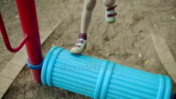 Маленькая красивая девочка занимается на спортивном тренажере в летнем городском парке . — стоковое видео