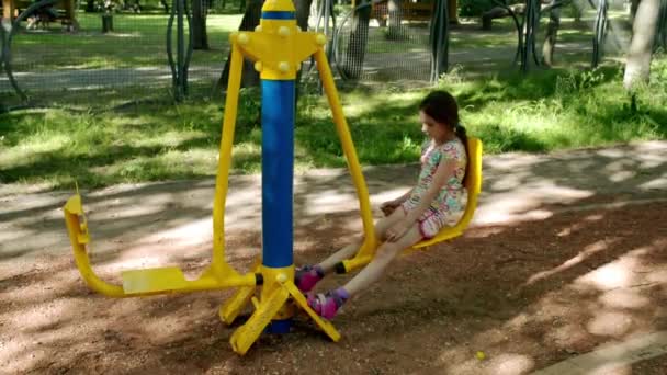 Lilla vackra flicka förlovad på sport utbildning apparater i sommar stadspark. — Stockvideo