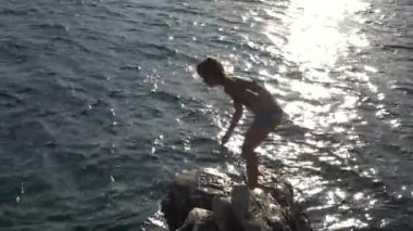 Küçük güzel kız taştan Hırvatistan Adriyatik sahil üzerinde denize atlama.