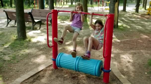 Δύο μικρά όμορφα κορίτσια που εκτελούν αθλητικό εκπαιδευτές-ενότητες στο πάρκο της πόλης το καλοκαίρι. — Αρχείο Βίντεο