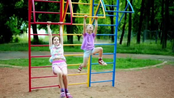 Zwei kleine schöne Mädchen treibt Sport am Barren im Sommerstadtpark. — Stockvideo