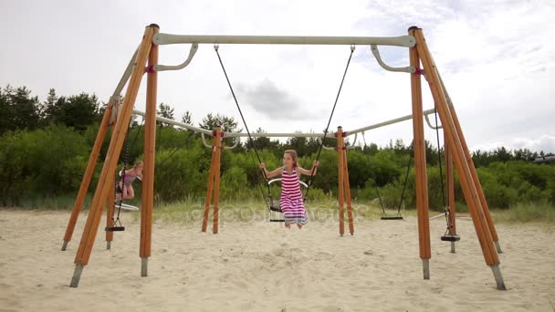 Slowmotion: Två små vackra flickor på swing Östersjön i Jūrmala, Latvia. — Stockvideo