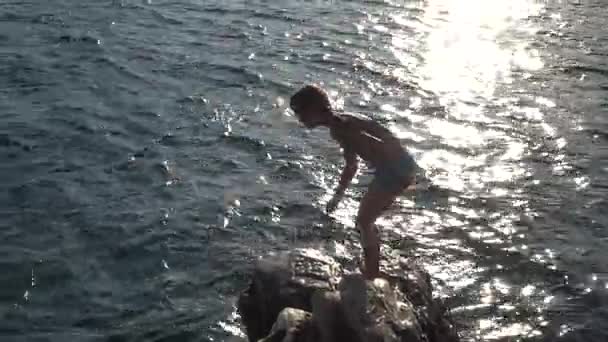 Kleines schönes Mädchen springt von Stein zu Meer an der Adriaküste von Kroatien. — Stockvideo
