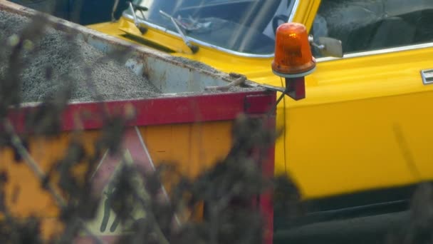 Camión de carrocería con grava y luces intermitentes activadas de color naranja sobre un fondo de una calle de la ciudad . — Vídeos de Stock