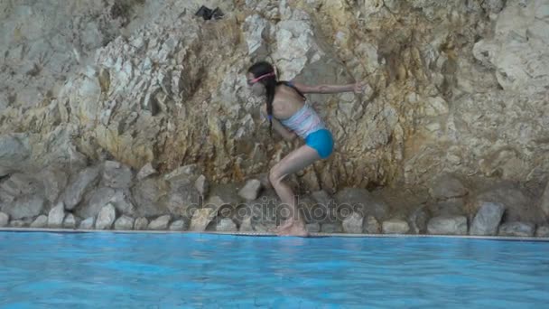 Slowmotion: Lilla vackra flicka hoppa i poolen med klart vatten. — Stockvideo