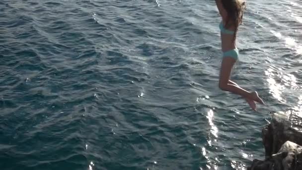 Slow Motion: Niña hermosa saltando de piedra al mar en la costa adriática de Croacia . — Vídeos de Stock