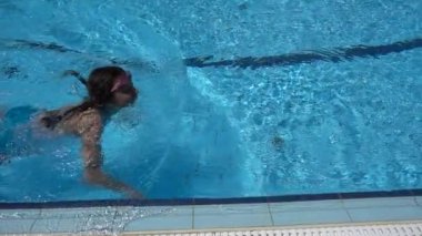 Güzel küçük bir kız ile temiz su havuzunda yüzüyor.