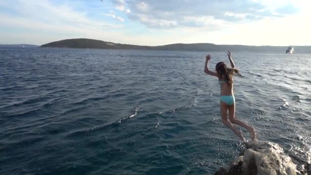 Slow Motion: Niña hermosa saltando de piedra al mar en la costa adriática de Croacia . — Vídeo de stock