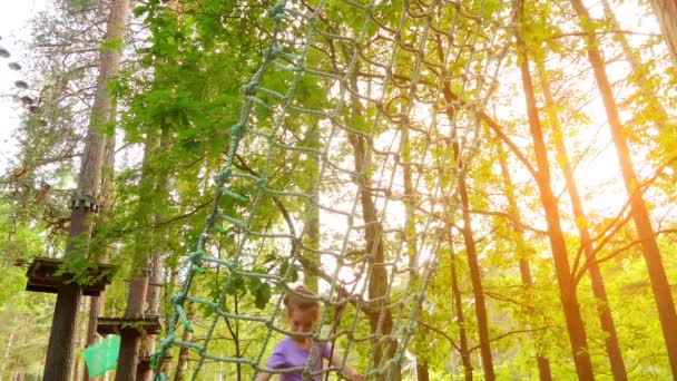 Mała dziewczynka w parku rozrywki. Przygoda park jest miejscem, które mogą zawierać szereg elementów, takich jak liny wspinaczkowe ćwiczenia, przeszkoda kursy i linii zip. Przeznaczone do rekreacji. — Wideo stockowe