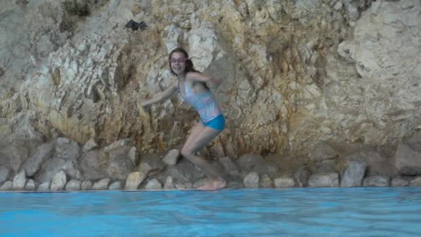 Movimento lento: Pequena menina bonita pulando na piscina com água limpa . — Vídeo de Stock