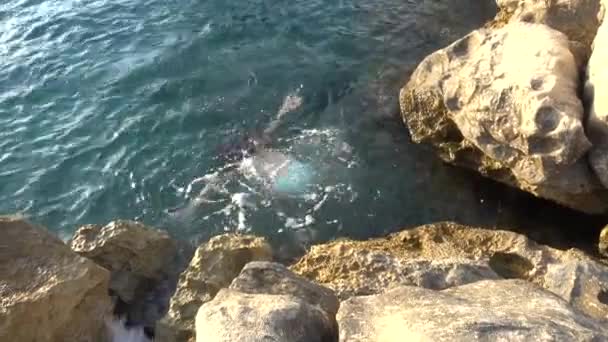 Mooi meisje springen uit steen naar zee op de Adriatische kust van Kroatië. — Stockvideo