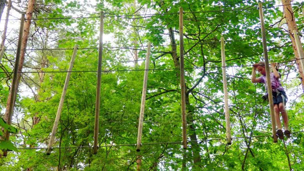 Menina pequena no parque de aventura. Parque de aventura é lugar que pode conter grande variedade de elementos, tais como exercícios de escalada de corda, cursos de obstáculos e tirolesa. Destinados a recreação . — Vídeo de Stock