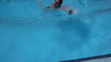 Ağır çekim: Güzel küçük bir kız ile temiz su havuzunda yüzüyor.