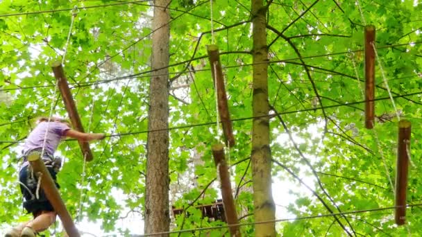 Kleines Mädchen im Abenteuerpark. Abenteuerpark ist ein Ort, der eine Vielzahl von Elementen enthalten kann, wie Seilkletterübungen, Hindernisparcours und Seilrutschen. Sie dienten der Erholung. — Stockvideo