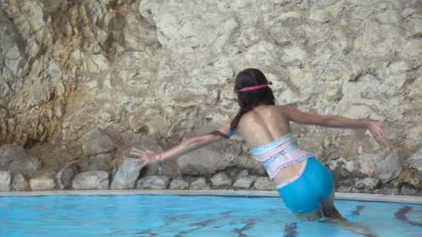 Zeitlupe: Kleines hübsches Mädchen springt mit klarem Wasser in Pool. — Stockvideo