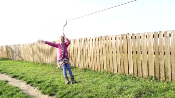 Lilla vackra flicka rider zipline. Zipline eller vagn är rep sträcks vid viss vinkel längs vilken, med karbin eller block, flyttar människor under gravitation. — Stockvideo