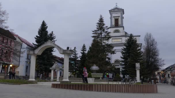 Duas meninas bonitas caminham perto da Igreja Evangélica da Santíssima Trindade na Namestie Egidia Street, Poprad, Eslováquia . — Vídeo de Stock