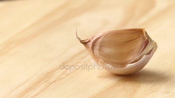 Circular motion: clove of garlic lies on wooden board. — Stock Video