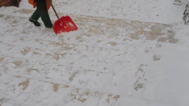 Turuncu tulum sokak işçisi merdiven adımlardan kürek ile kar temizleme.