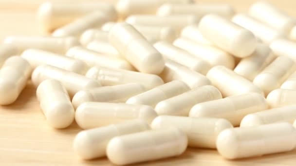 Cápsulas medicinales blancas giran sobre mesa de madera — Vídeos de Stock