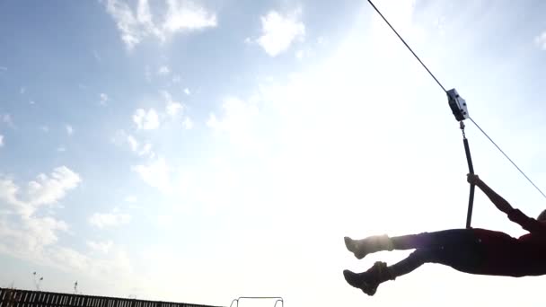 Pequeña chica hermosa está montando tirolina. Zipline o carro es cuerda estirada en cierto ángulo a lo largo del cual, con la carabina o el bloque, la gente se mueve bajo gravedad . — Vídeos de Stock