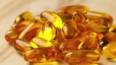 kapsül balık yağı ile tahta masada yatıyor ve döner