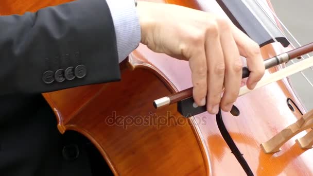 Музикант в костюмі грає на віолончелі крупним планом. Віолончель або віолончель вклоняється, а іноді виривається, струнний інструмент з чотирма струнами, налаштованими в ідеальних п'ятдесятих — стокове відео