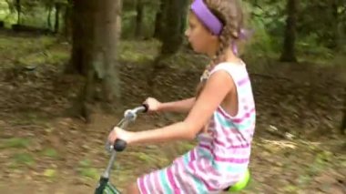 Güzel genç kız yaz orman yollarında asfalt boyunca bisiklet sürme.