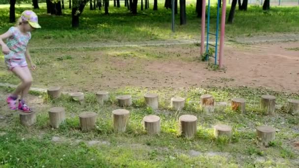 Niña corre a través de carrera de obstáculos deportivos en el parque de la ciudad de verano — Vídeos de Stock