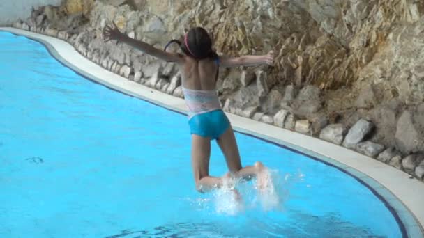 Movimento lento: Pequena menina bonita pulando na piscina com água limpa . — Vídeo de Stock