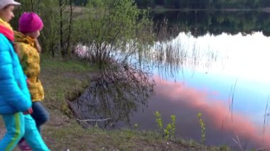 İki küçük göl kıyısında günbatımı arka plan üzerinde duran kız kardeş.