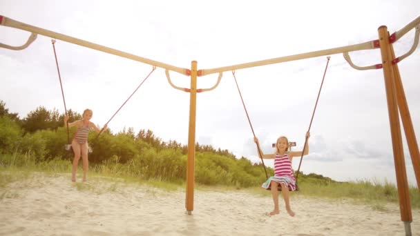 Slowmotion: Två små vackra flickor på swing Östersjön i Jūrmala, Latvia. — Stockvideo