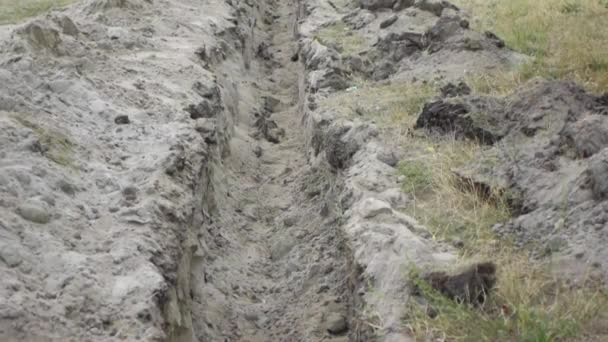 Due ragazzine saltano sopra un fosso di terra, scavato per la posa di tubi . — Video Stock