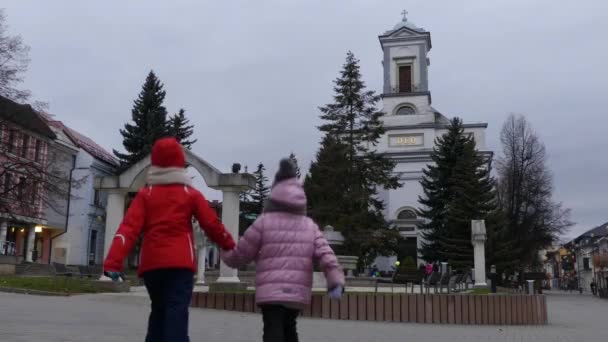 İki güzel kızın Protestan Kilisesi, Holy Trinity yakınındaki Namestie Egidia Street, Poprad, Slovakya üzerinde yürümek.. — Stok video