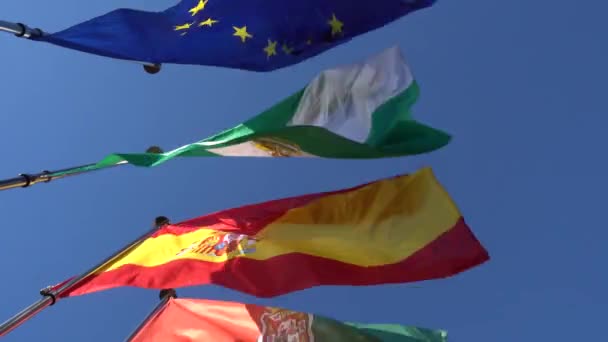 Flags of European Union, Spain, Andalusia and Granada flutter against blue sky. — Stock Video