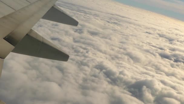 Tragfläche eines Flugzeugs fliegt in großer Höhe über weiße, flauschige Wolken — Stockvideo