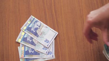 Eller tarafından ahşap masa üzerinde Bulgar levs koyulur.