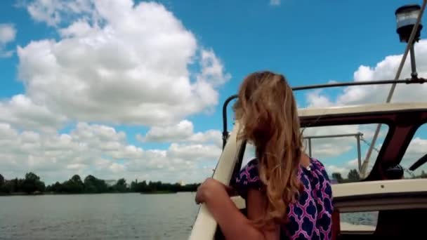Schönes kleines lächelndes Mädchen mit langen Haaren schwimmt auf Boot auf Fluss unter großer Betonbrücke. — Stockvideo