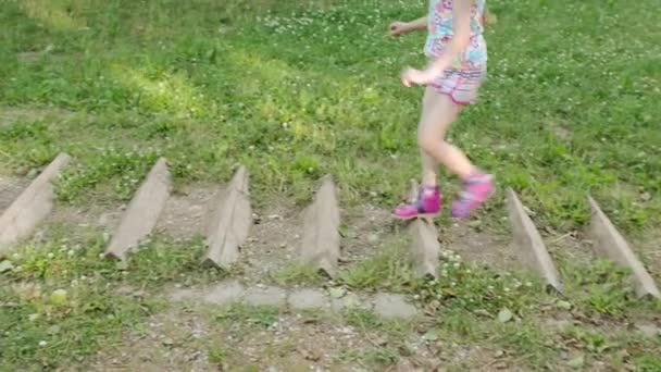 Niña corre a través de carrera de obstáculos deportivos en el parque de la ciudad de verano — Vídeos de Stock