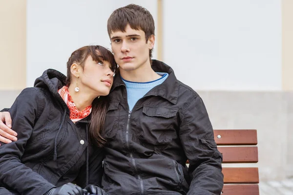 Young beautiful couple is sitting on bench — Stock Photo, Image