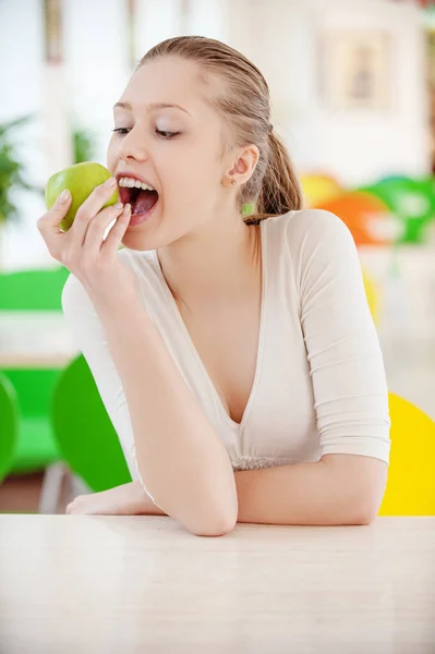 Young beautiful woman bites off a big green apple — Stock Photo, Image