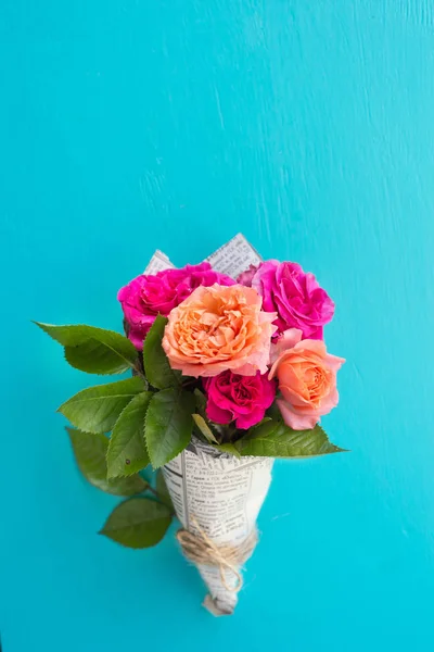 Rosas frescas de color rosa y naranja en la cubierta de papel sobre fondo azul —  Fotos de Stock