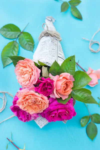 Rosas frescas de color rosa y naranja en la cubierta de papel sobre fondo azul —  Fotos de Stock