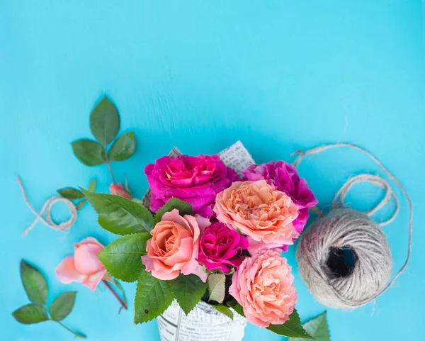 Fresh pink and orange roses in paper cover over blue background — Stock Photo, Image